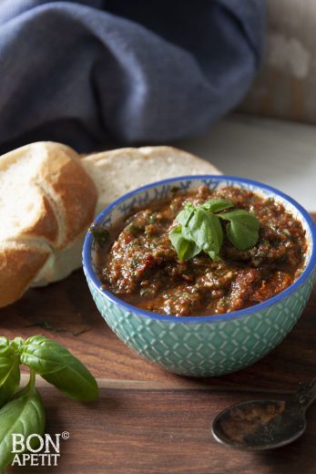 Rode pesto met een blaadje basilicum in een kom