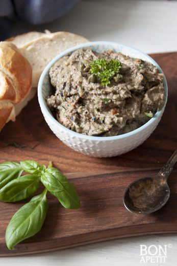 Tapenade met tonijn, zwarte olijven, basilicum en olijven op een plankje met brood