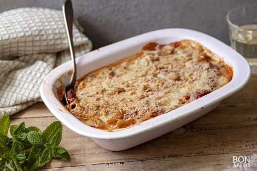 pastitsio met penne en gehakt op houten plankje