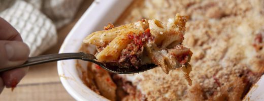 lepel met Griekse pastitsio penne, gehakt en bechamelsaus